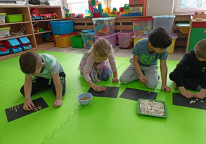 Dzieci w skupieniu tworzą fasolkowe obrazki na dowolny temat.